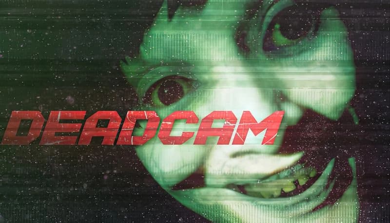 Deadcam: Distorted eerie face with wide grin on a grainy, glitchy screen. Greenish tint and digital noise create unsettling scene.