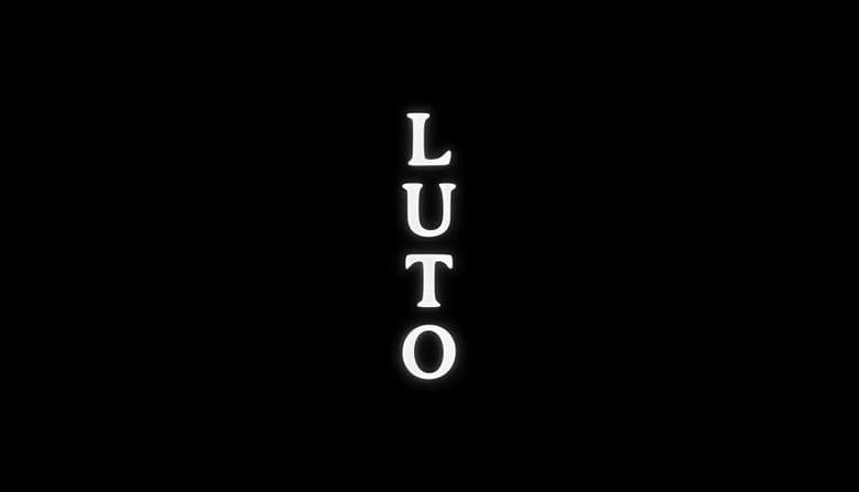 Luto: Vertical white serif letters spell "LUTO" on a black background, each letter glowing softly to create contrast.