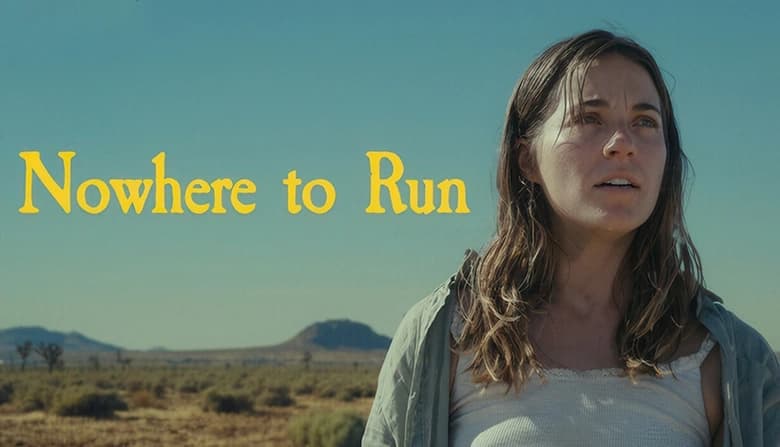 Young woman with long brown hair gazes intently forward in a dusty desert landscape with distant hills and a clear blue sky.