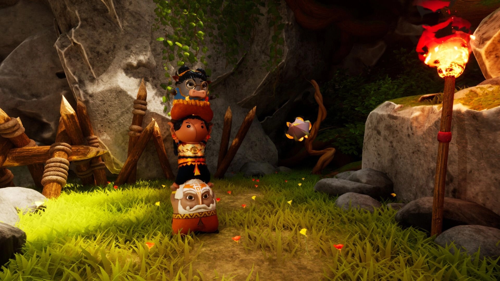 Aikyam: Three stacked characters in forest clearing with stone, wooden fence, and glowing torch nearby.