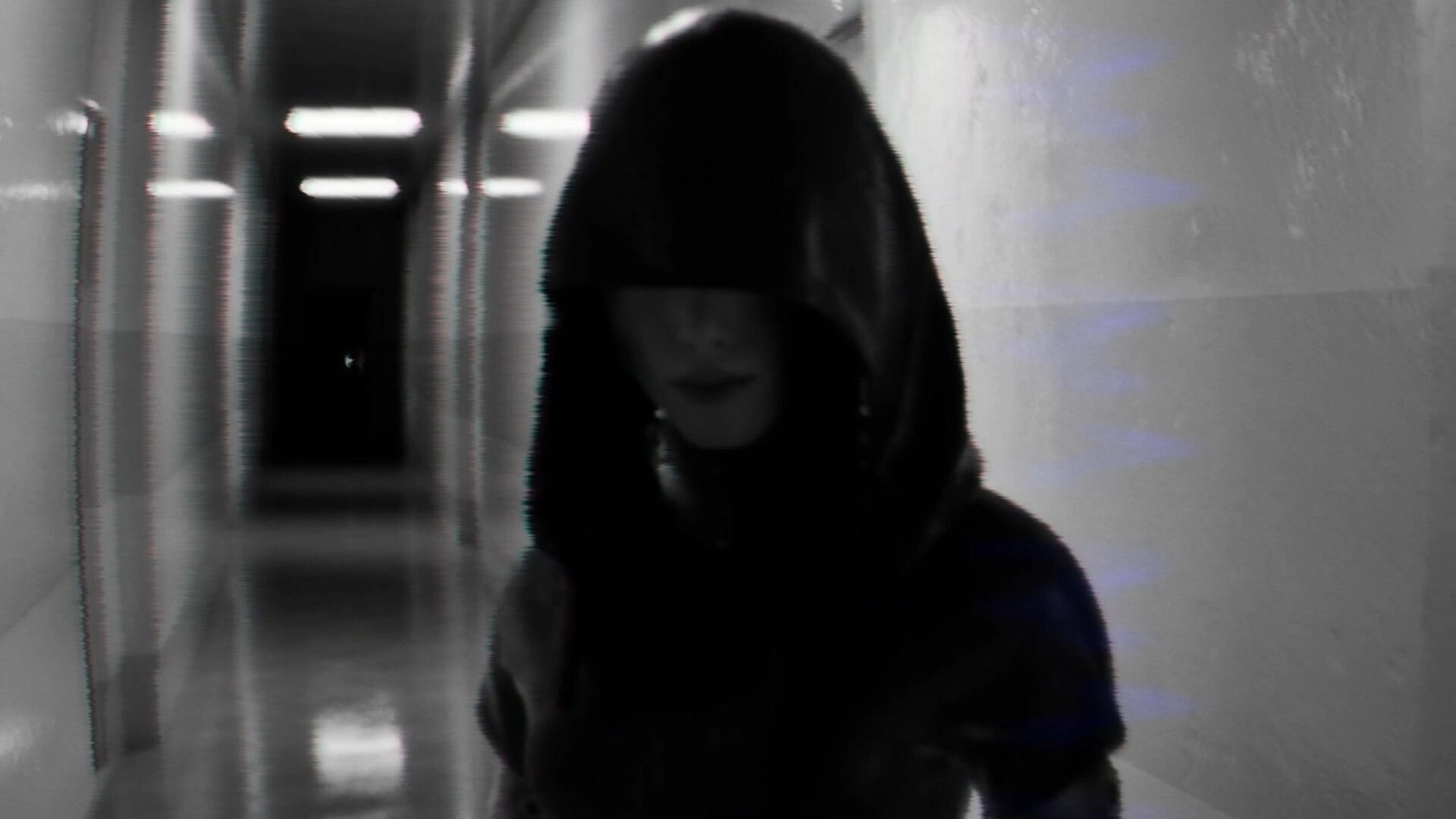 BrokenLore: Hooded figure with face obscured stands in a blurry, fluorescent-lit hospital corridor.