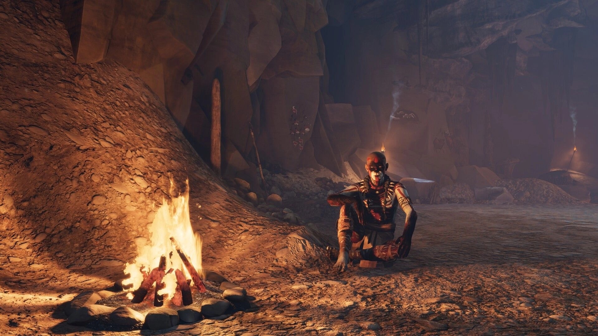 Kiipluu: Face-painted survivor resting by a campfire inside a rocky cave lit by torches and smoke.