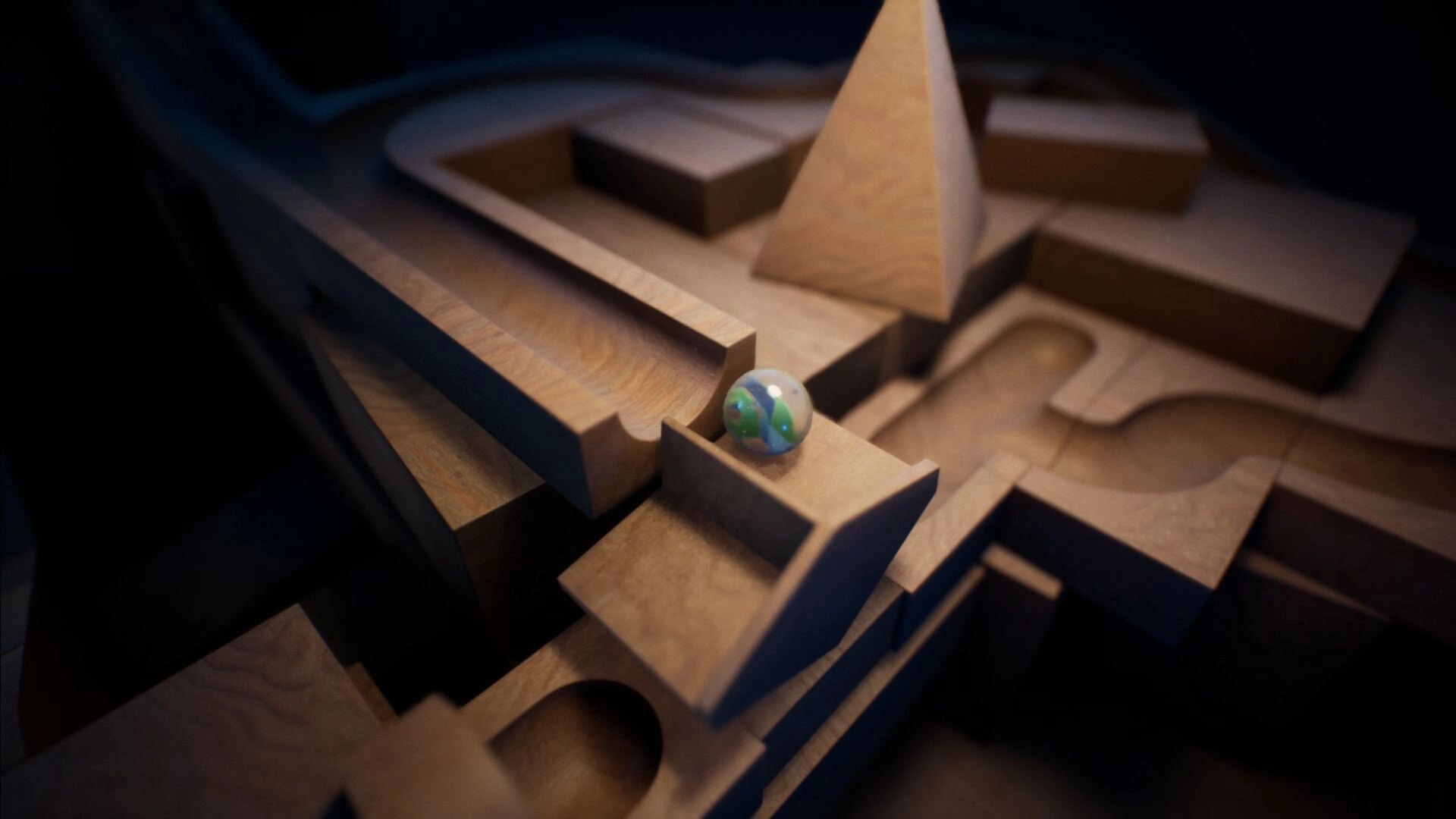Marblearium: Glass marble poised on a wooden track junction amid carved ramps and a pyramid block.