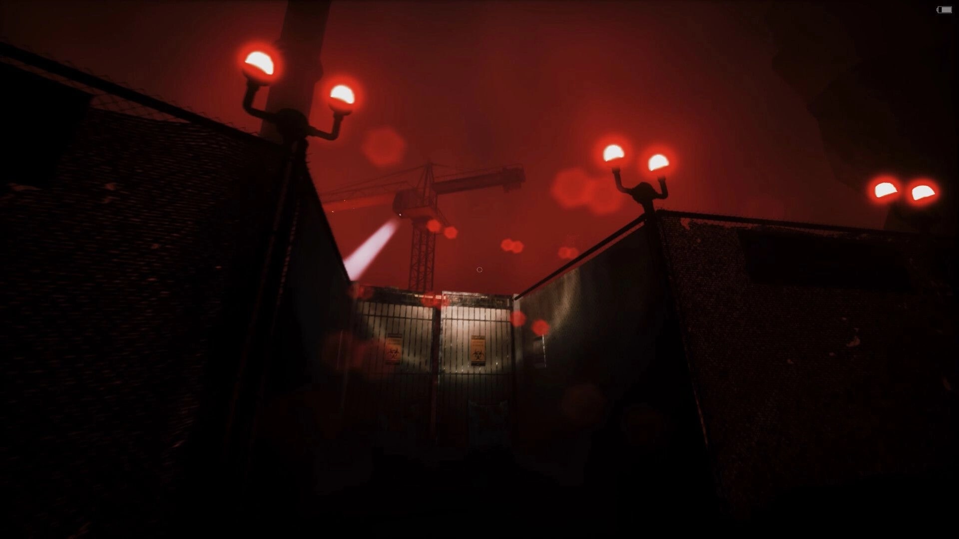 Netherwake: First-person view facing a fenced gate under red fog, crane spotlight and lamps glowing.
