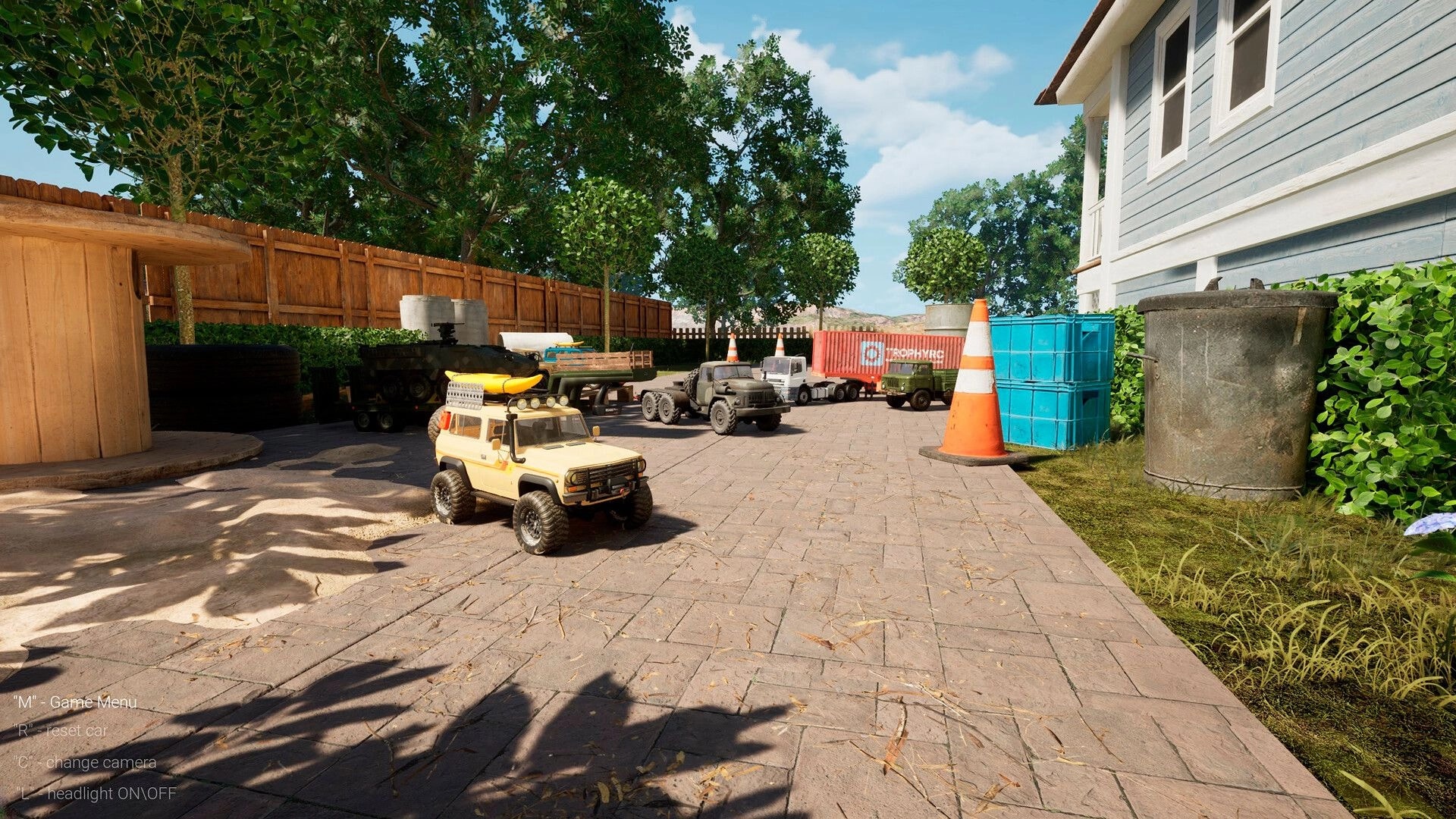 TrophyRC: Yellow RC crawler parked in yard obstacle area with cones, trucks, and container props.
