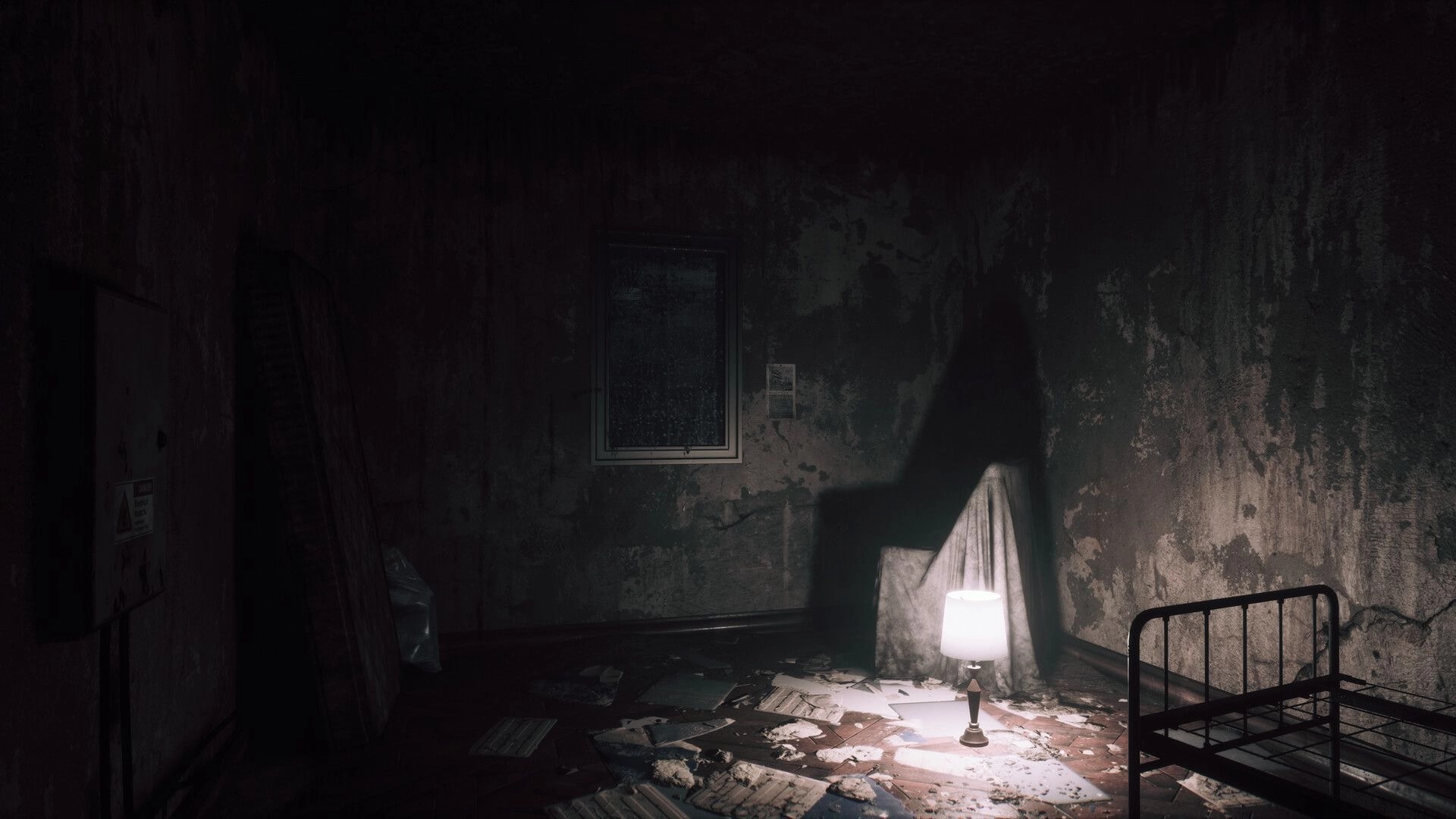 UNHOST: Dim hospital room lit by a table lamp, with a rusted bedframe and peeling walls.