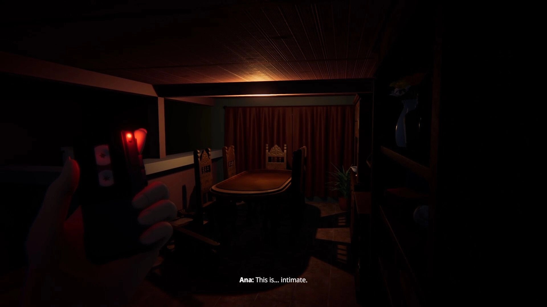 Animas Prologue: Ana holds device in dimly lit dining room with wooden table and chairs, curtains drawn.