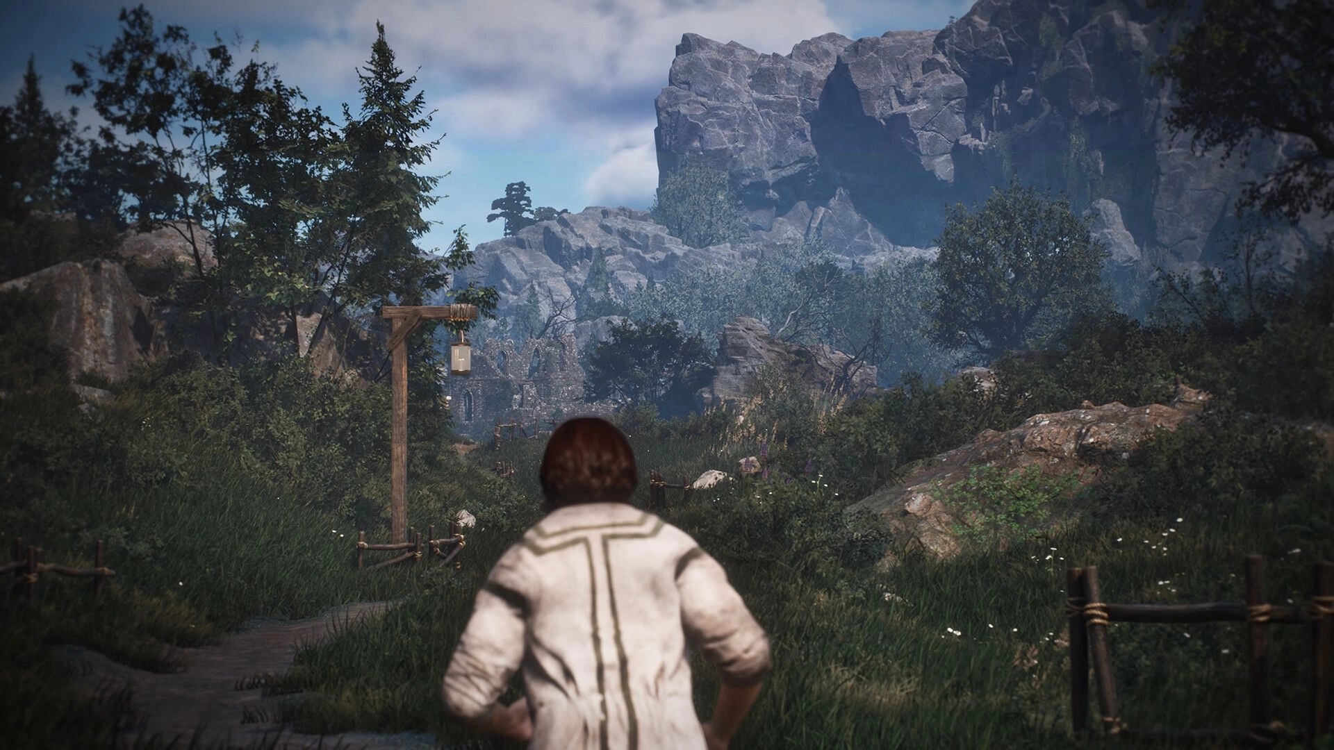 Asterfel: Third-person adventurer on a grassy trail facing rocky cliffs, trees, and distant ruins.