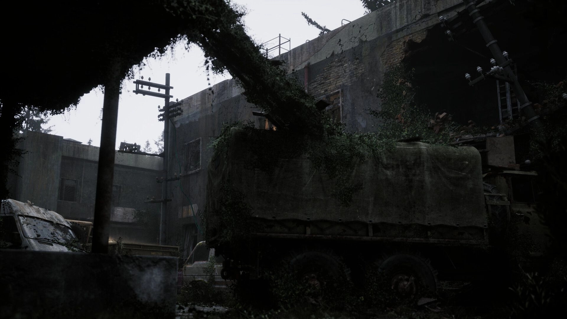 Beautiful Light: Overgrown military truck in abandoned courtyard with crumbling walls and power lines.