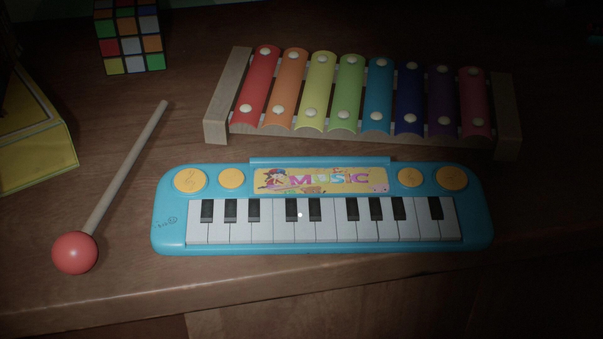 Berghotel Heist: Toy keyboard and xylophone on wooden table in dimly lit room