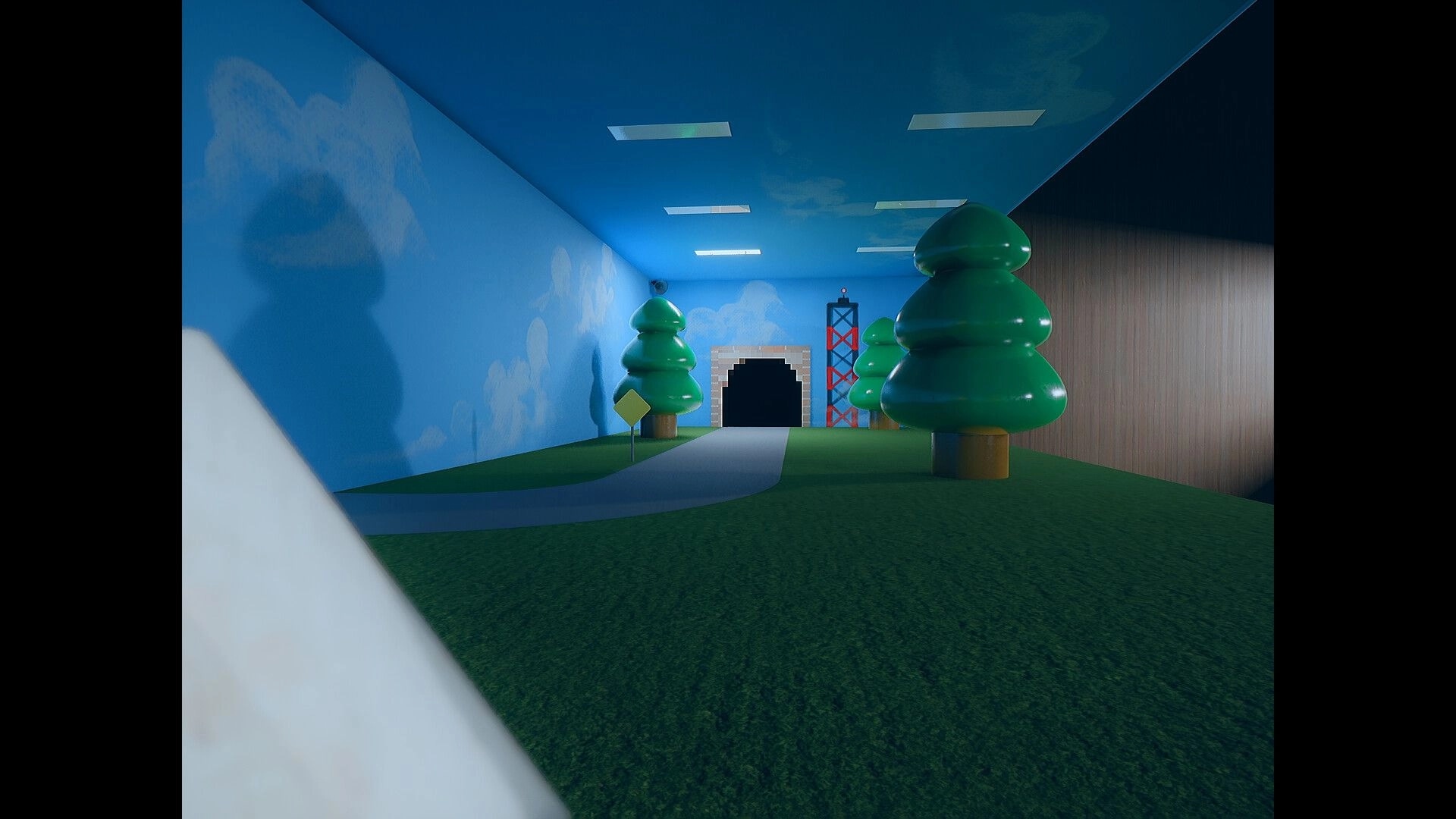 Beyond The Frame: First-person view down a winding path to a tunnel in a toy-like indoor park room.