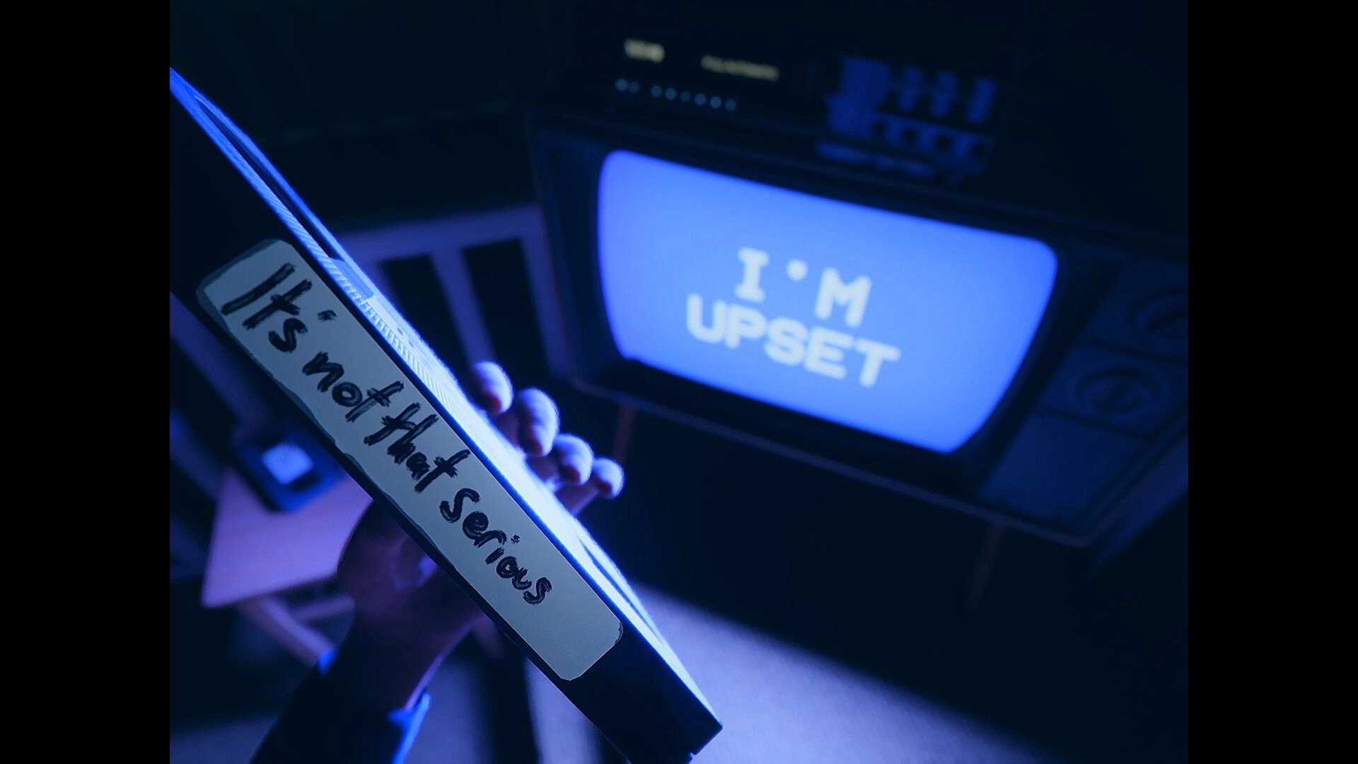 Beyond The Frame: Holding a VHS tape labeled "It's not that serious" near a TV reading "I'M UPSET".