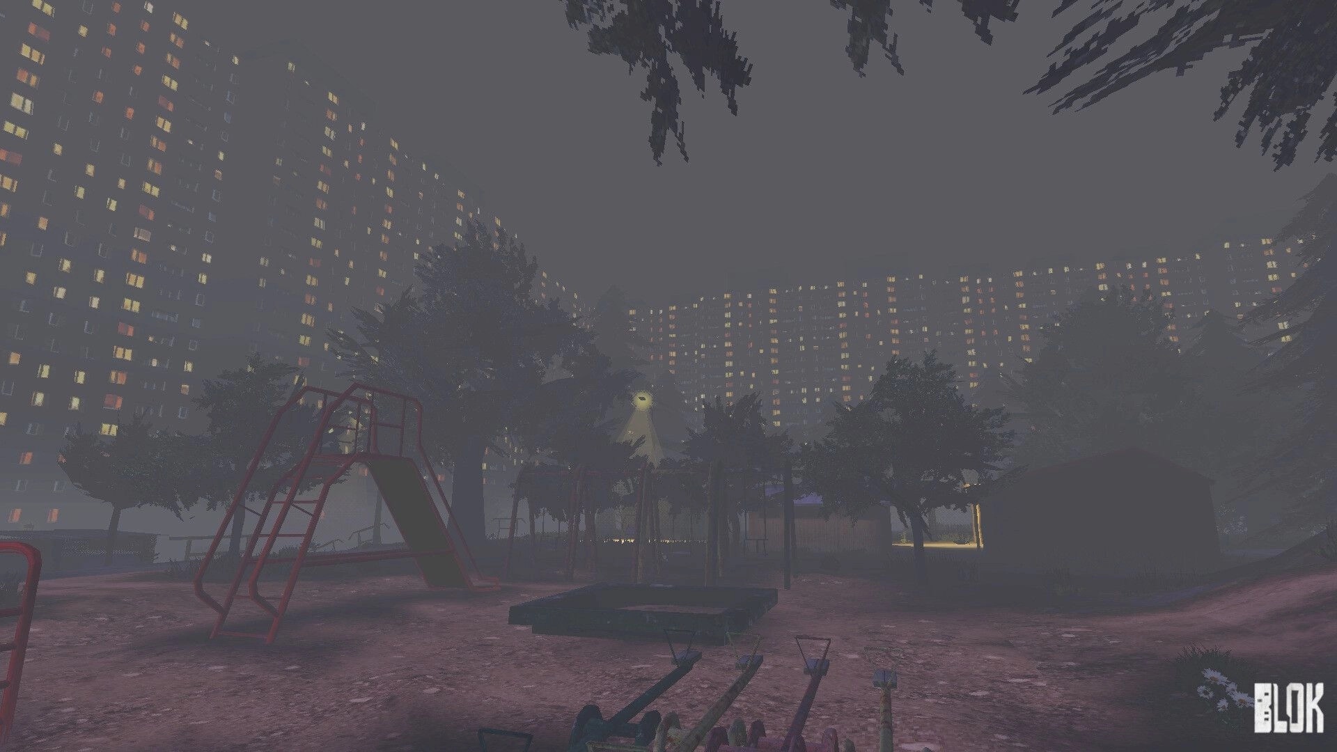BLOK: Foggy playground with slide and seesaw beneath looming apartment blocks at night.