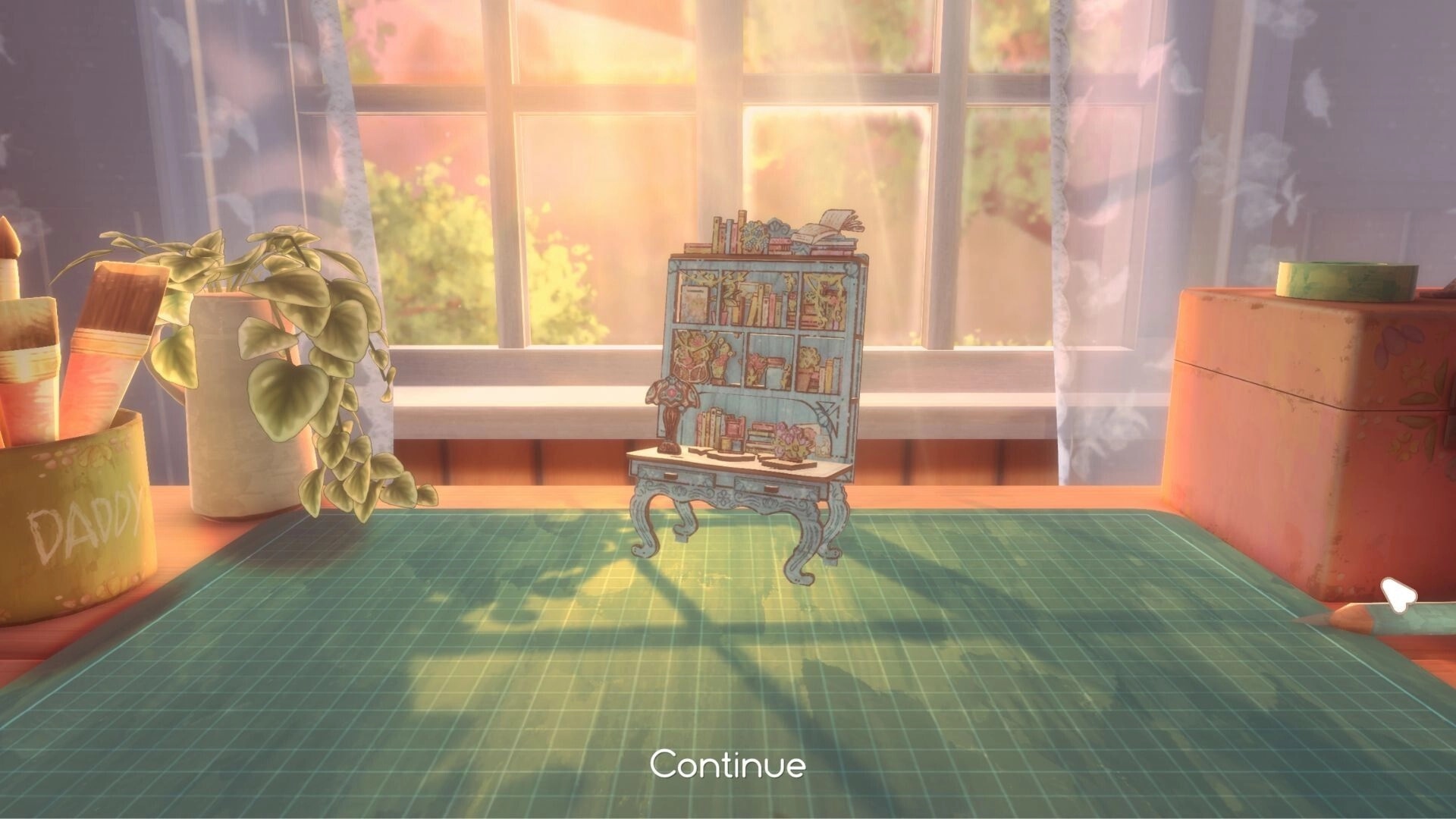 Book Nook: Miniature bookshelf desk diorama on cutting mat with Continue prompt in sunny craft room.