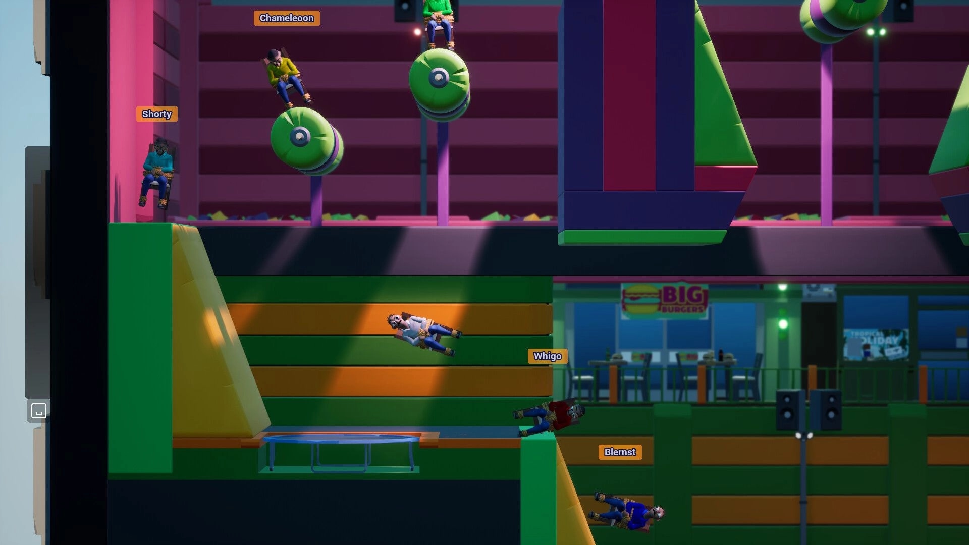 Bound To Fail: Four chair-bound players tumble past green bumpers in a colorful indoor obstacle course.