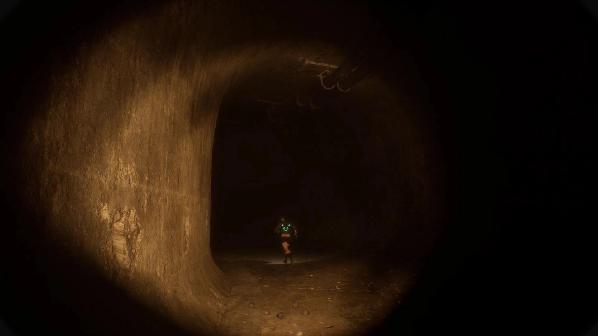 BrokenLore: Player runs toward a shadowy tunnel bend with overhead pipes in dim amber light.