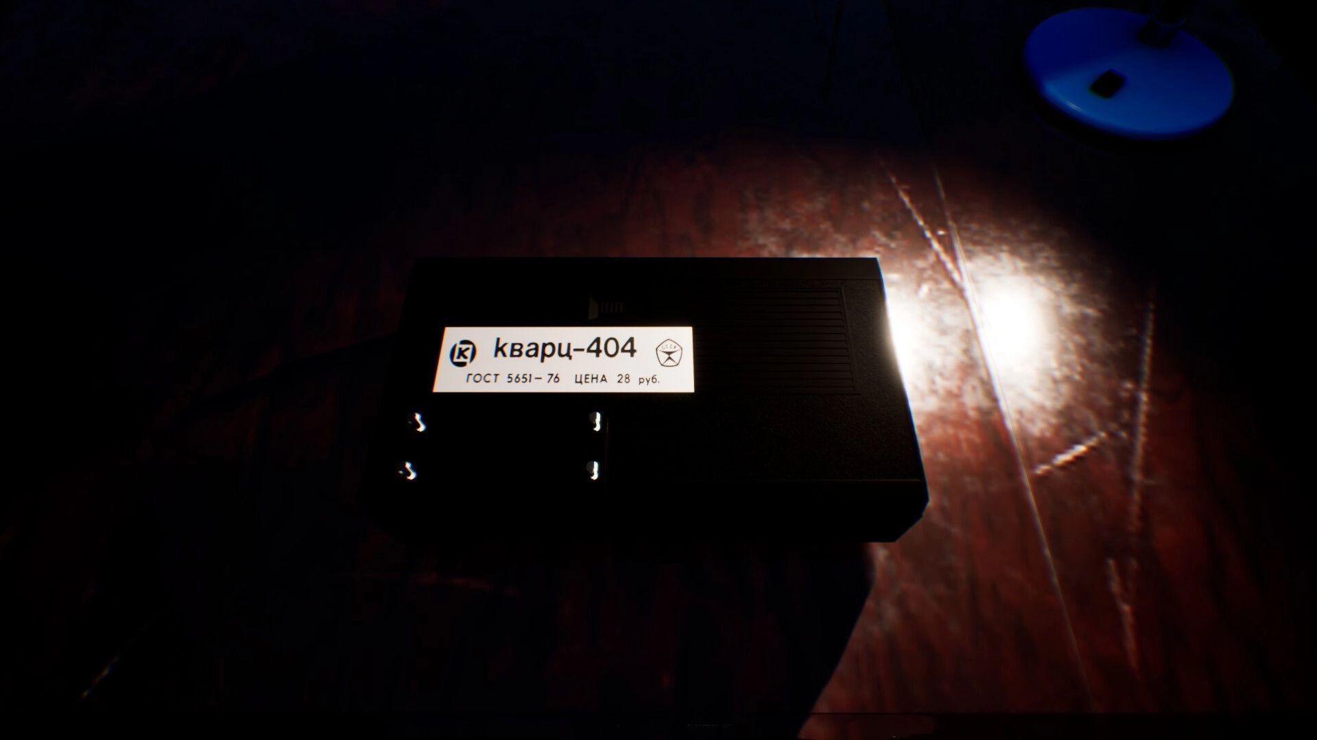 Change: Close-up of a Kvarts-404 cassette tape on a wooden counter under dim blue lamp light.