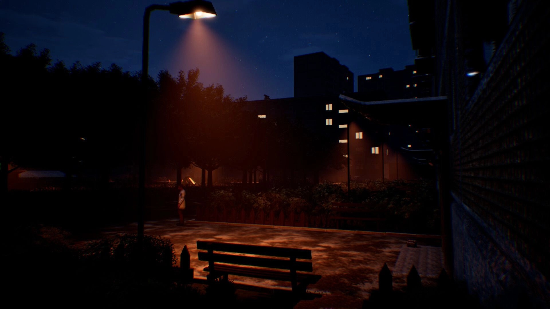 Change: Nighttime park walkway under a streetlamp, bench in foreground and apartment blocks beyond.