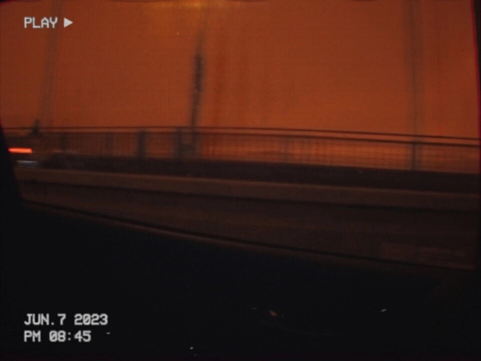 CHILDREN OF SATURN: Car interior view with bridge under orange sky, VHS tape overlay in foreground