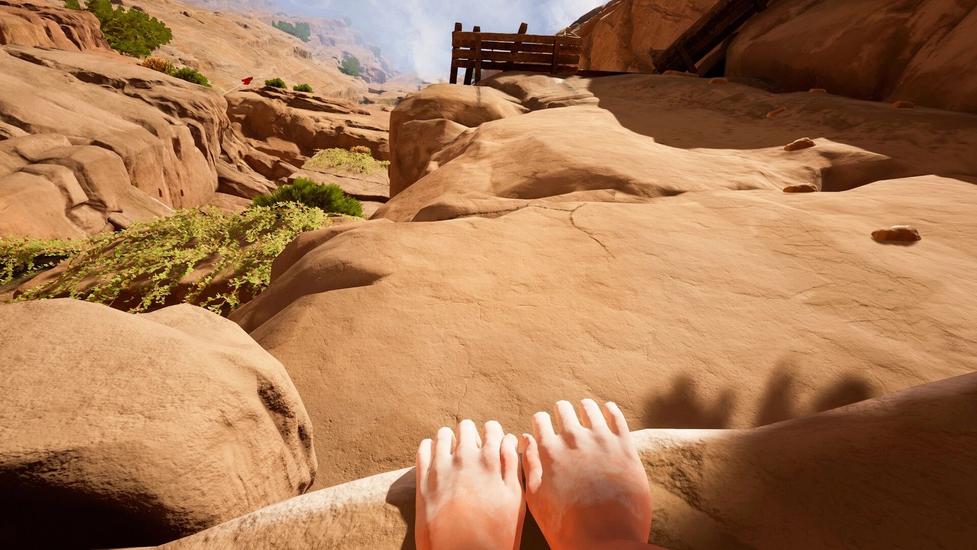 CLIMB IT!: First-person view of hands gripping a cliff edge with a wooden platform above in desert terrain.