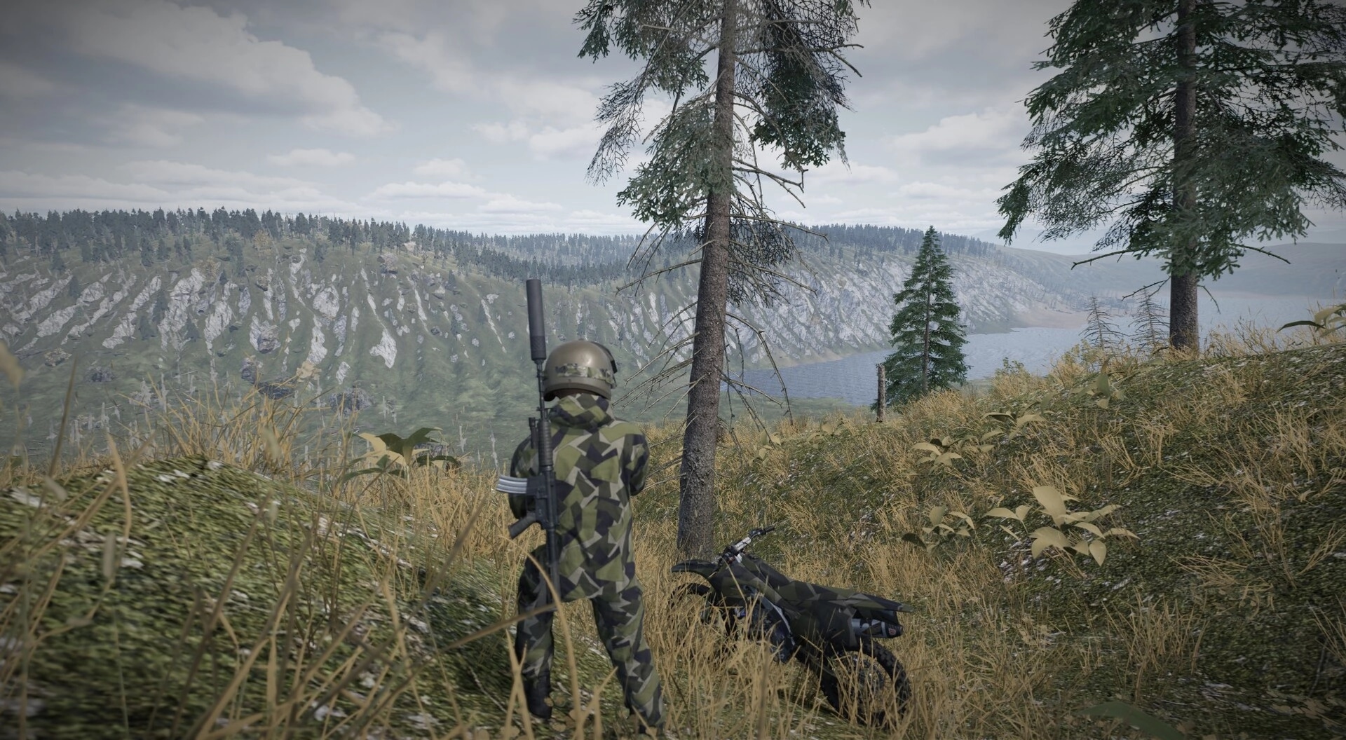Cold Response: Soldier in camo stands by a dirt bike on a hillside overlooking lake and cliffs.