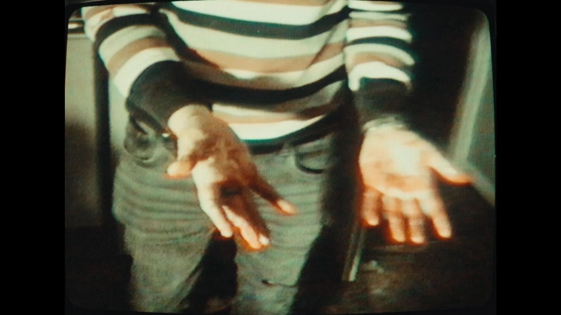 Dead Format: Close-up of character’s blood-stained hands in dimly lit room in 1990s Scotland setting