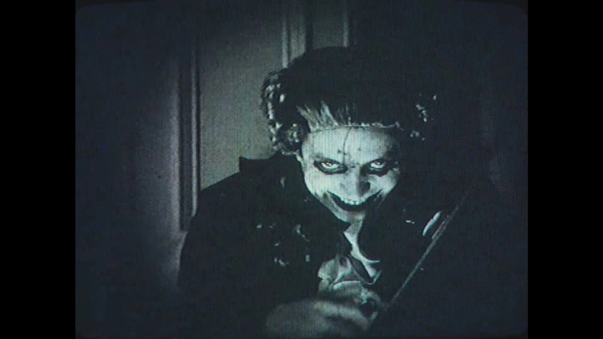 Dead Format: Creepy figure grinning in dimly lit room, reminiscent of old horror films