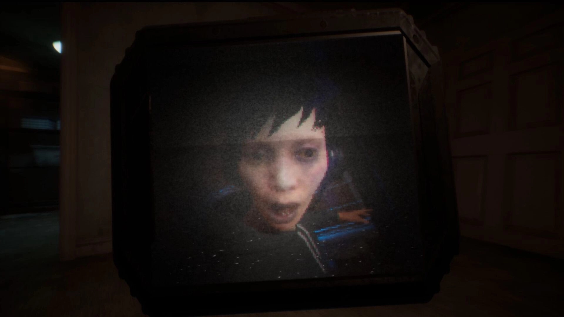 Deadcam: Margo's distressed face on a flickering monitor inside a dimly lit, eerie hallway.