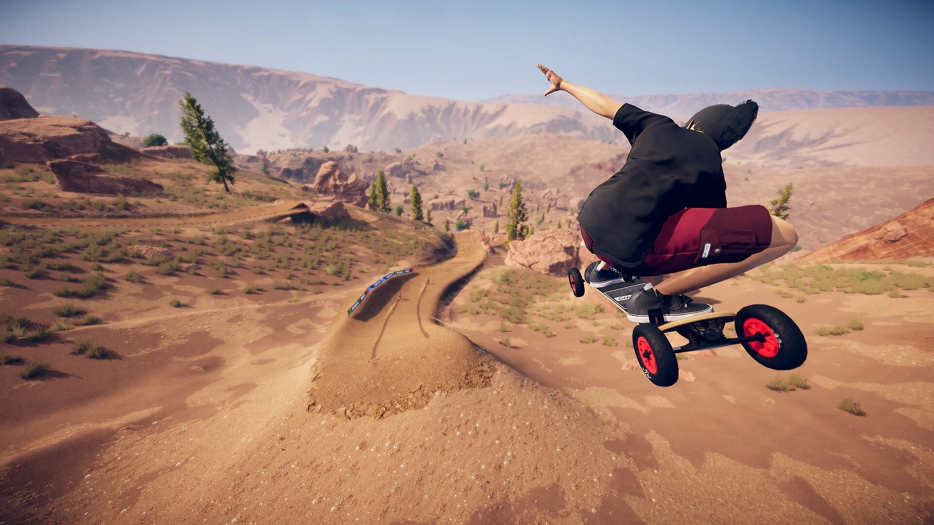 Descenders Next: Player performs mid-air trick on mountain board in desert landscape with winding trails
