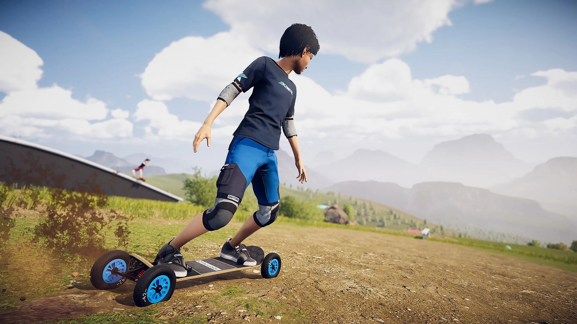 Descenders Next: Rider carving downhill on dirt track with mountains and clear skies in the background