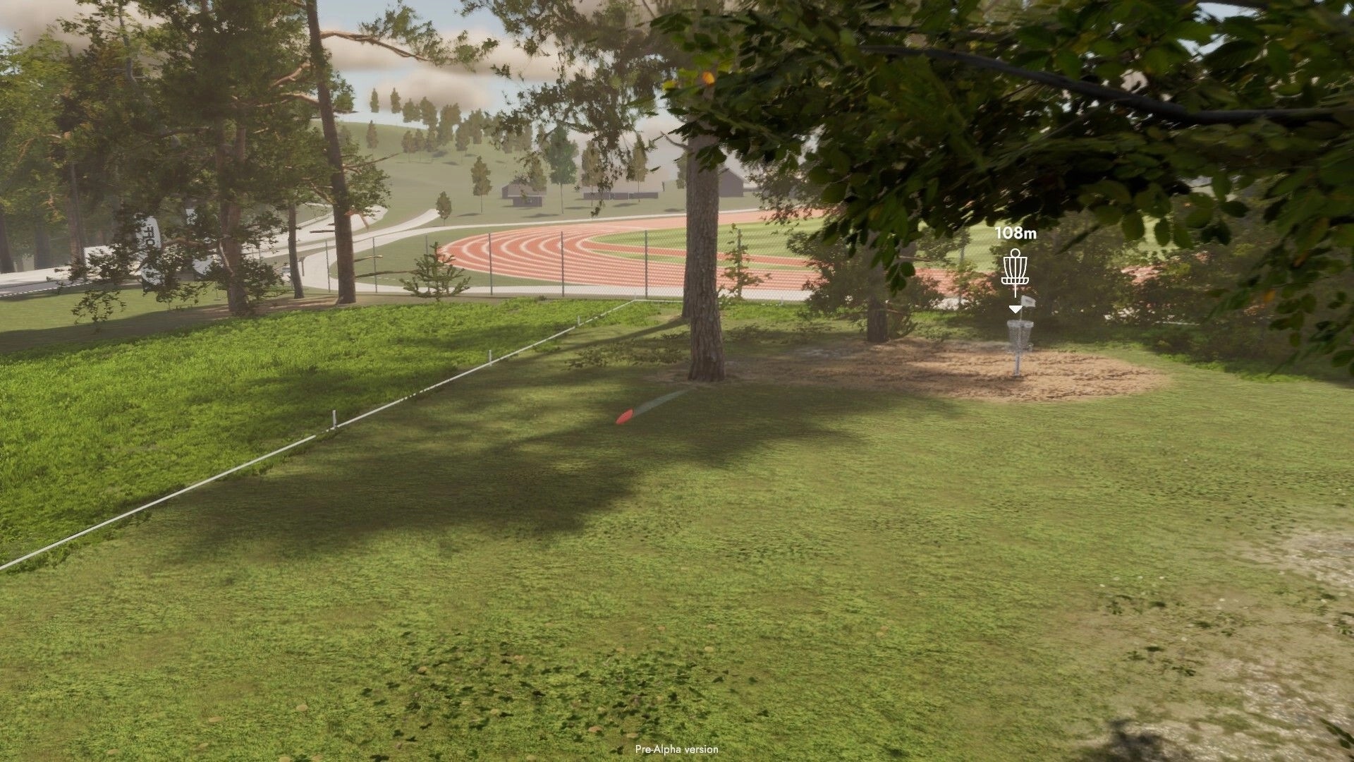 Disc Golf Masters: Disc flying towards basket in a grassy park with trees and a track in the background.