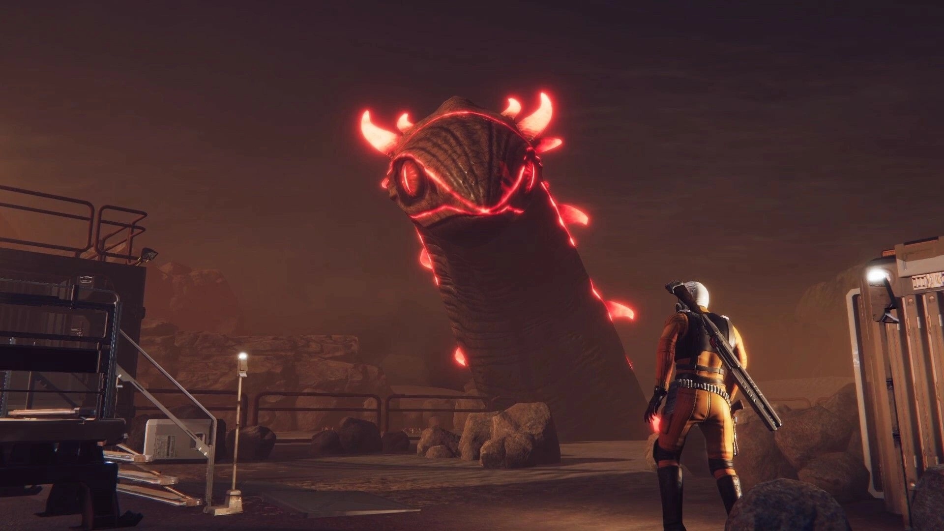 Drake Frontier: Player faces giant glowing worm creature in an industrial outpost setting at night