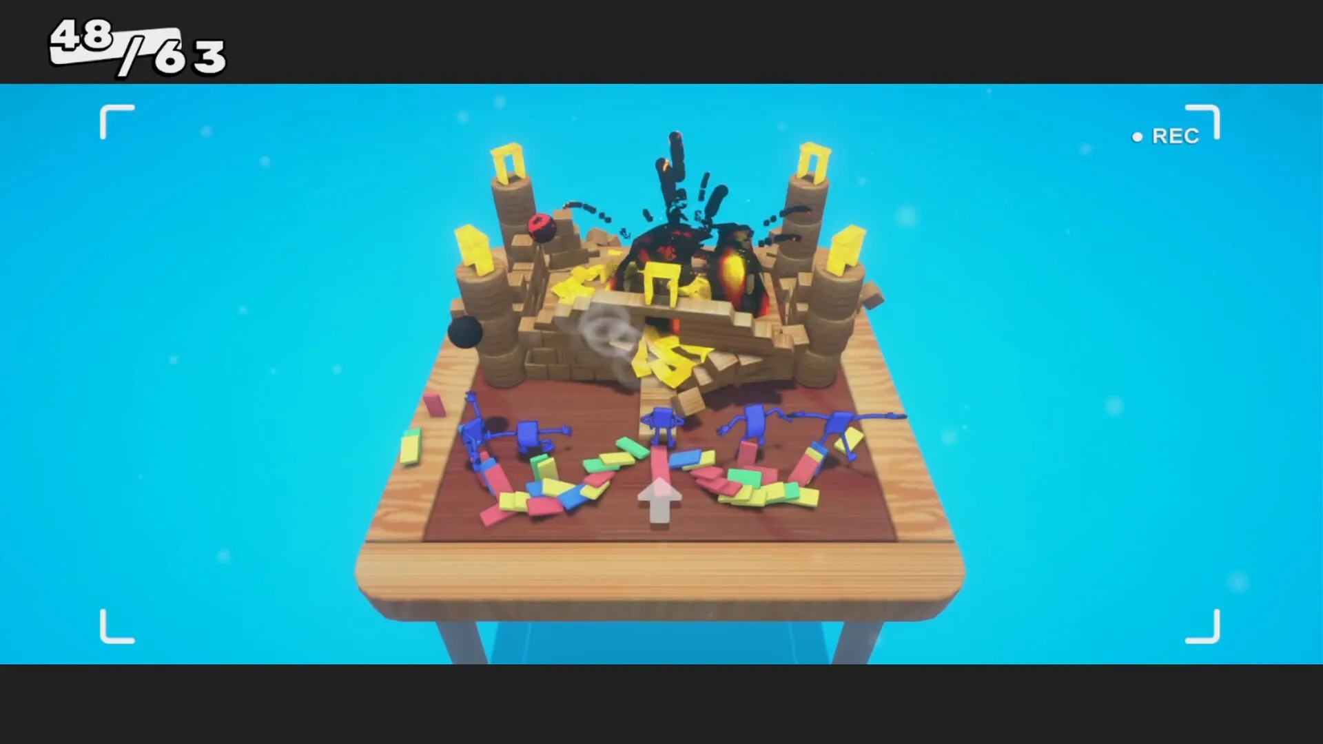 Dumbino: Colorful dominoes toppled by explosion on wooden table with score 48/63 in top left corner