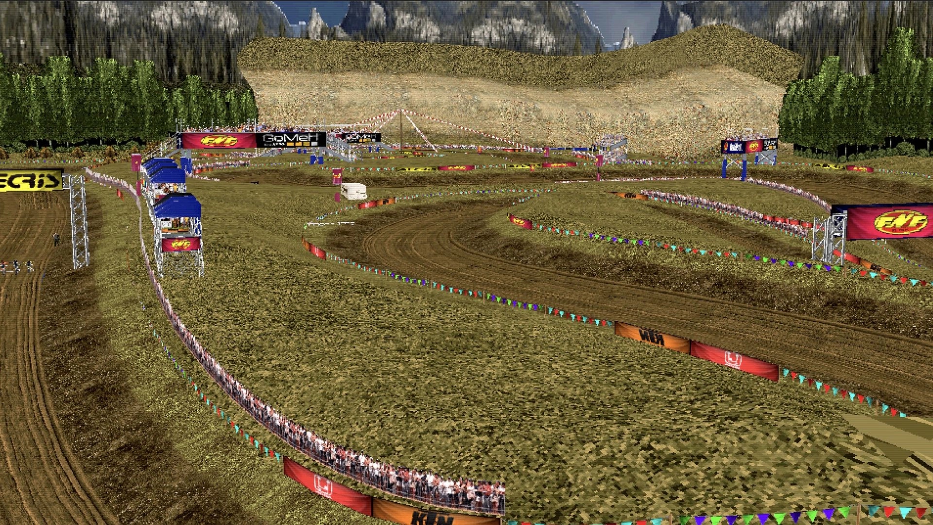 DüRT: Wide view of winding dirt motocross track with sponsor banners, stands, and trees by hills.