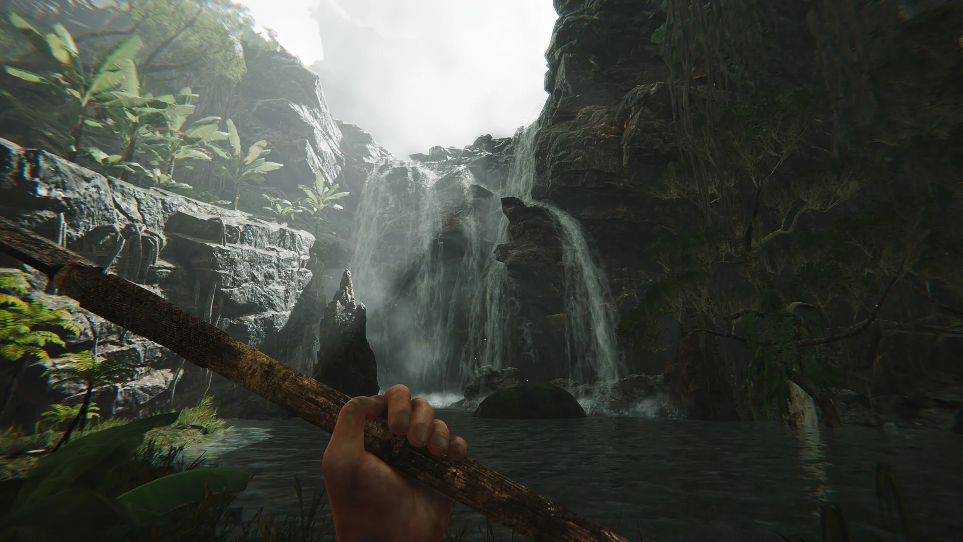 FEROCIOUS: Player holds spear in lush jungle setting with towering waterfall cascading over rocks.