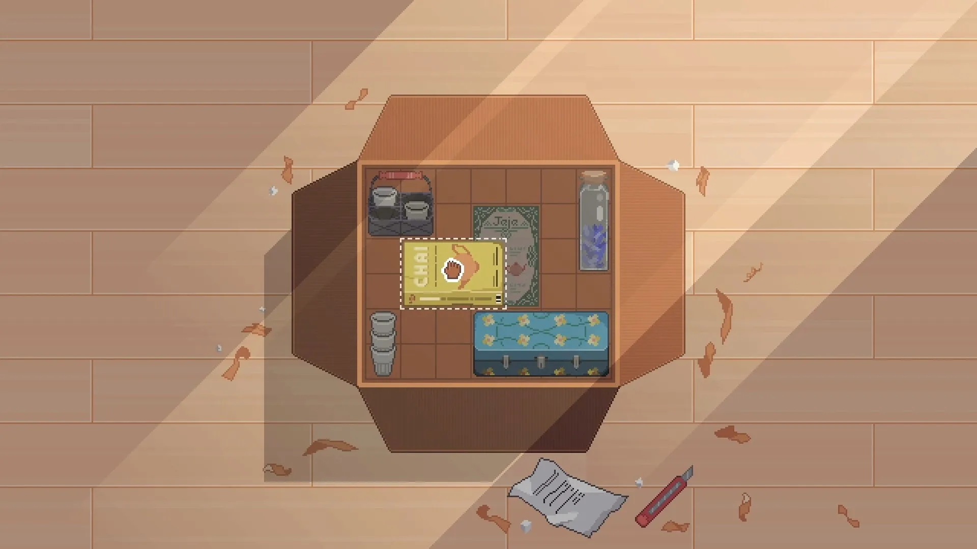 Fishbowl: Overhead view of a wooden table with chai packet, cups, papers, and scattered leaves on floor.