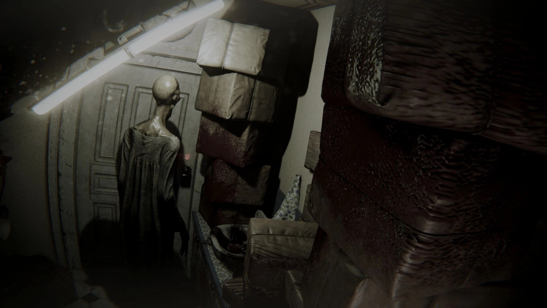 Flick: Gaunt figure stands by a door in a cluttered room, lit by a flickering tube light above.