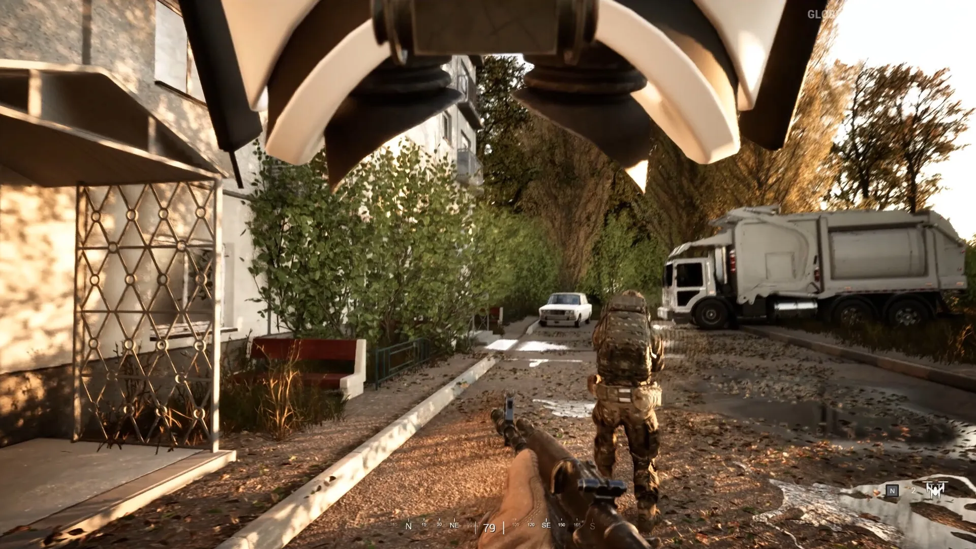 Glory To The Heroes: Soldier advances through a deserted street with a truck and trees in the background.