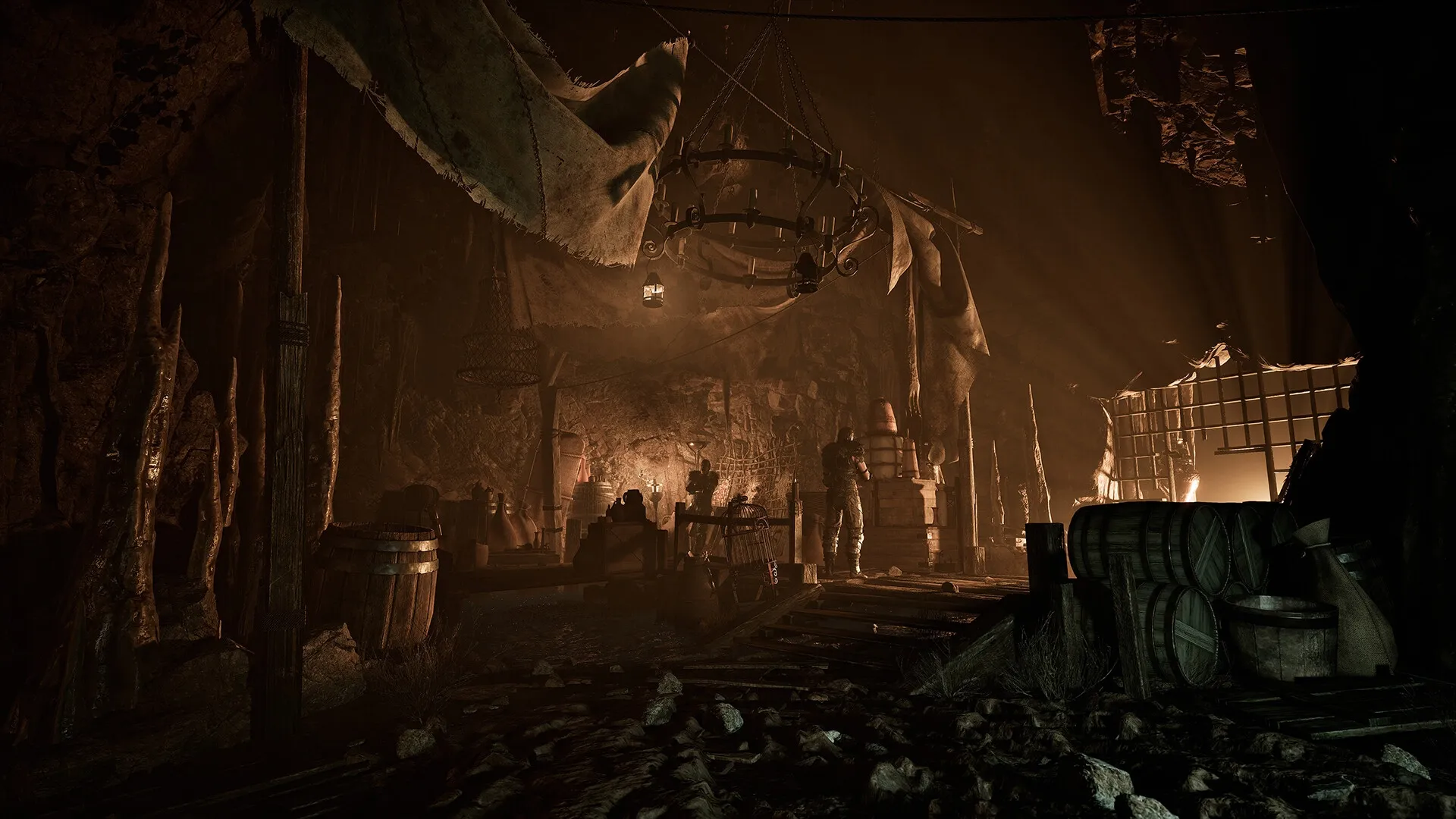 Gothic 1 Remake: Dimly lit cavern with barrels, crates, and a lone figure standing near a wooden structure