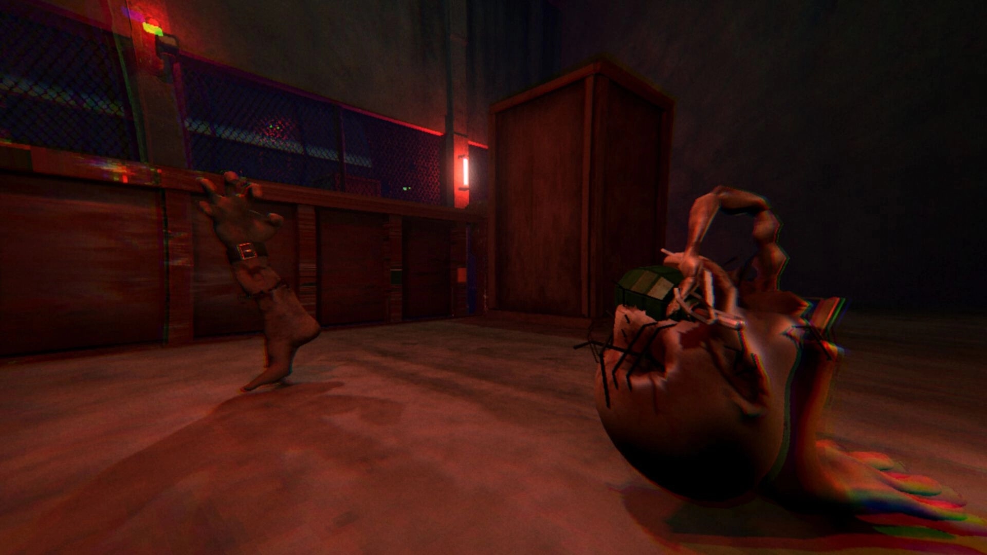 HandFoot: First-person view holding a grenade in a red-lit fenced warehouse with a severed arm enemy.