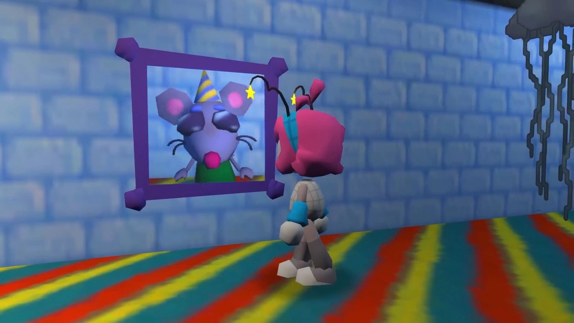 Home Paige: Paige faces a framed mouse portrait on a blue brick wall in a rainbow-striped hallway.