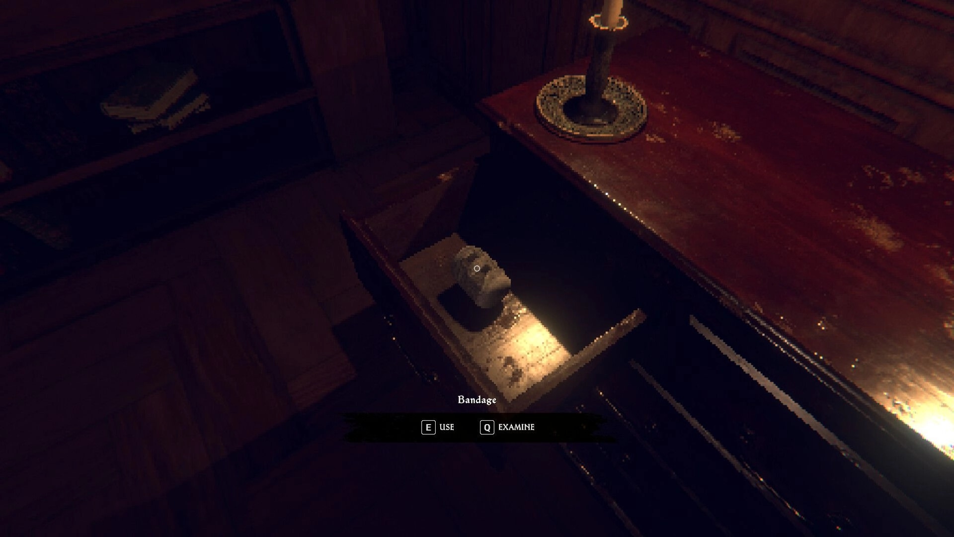 House of Saturn: Crosshair on bandage in open drawer with E Use and Q Examine prompts in dim room.