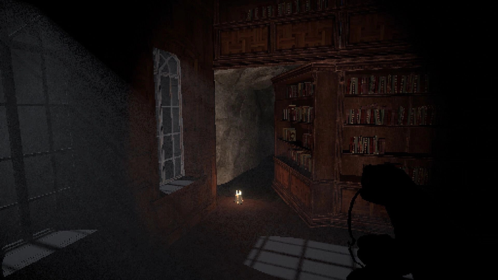 House of Saturn: Candle lit on floor beside tall bookshelves in a shadowy library corridor by window.