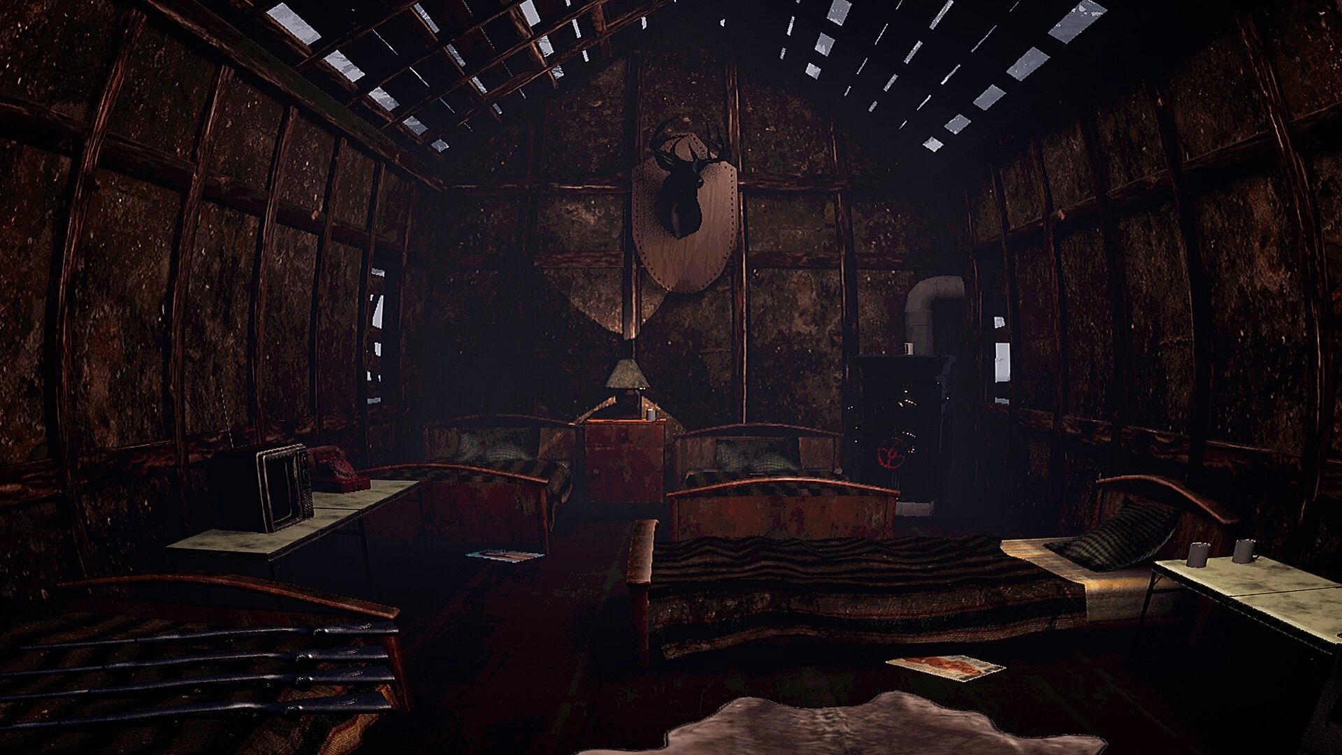 Huntin' Buddies: Inside a rusty cabin with beds, tables, mounted deer head, and stove pipe.