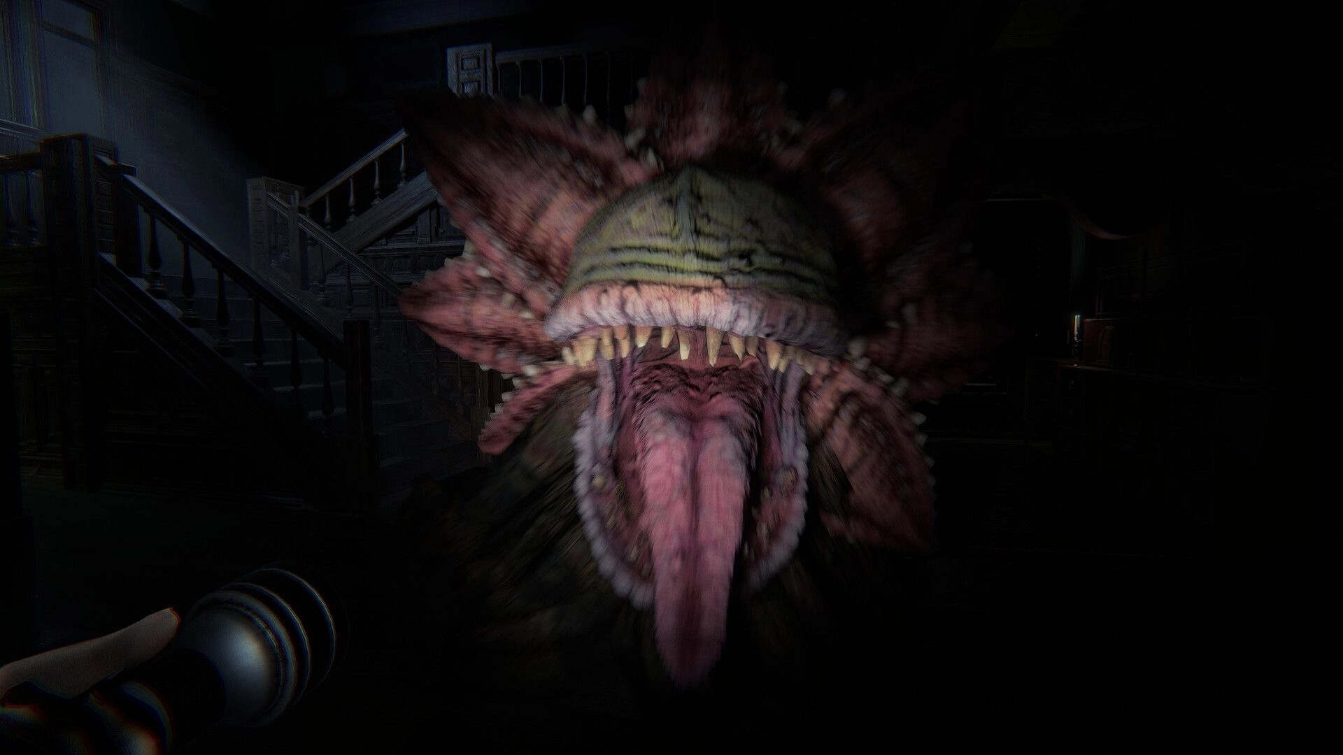 Invokyr: First-person jump scare as a fanged monster lunges in a dark mansion hallway by stairs.