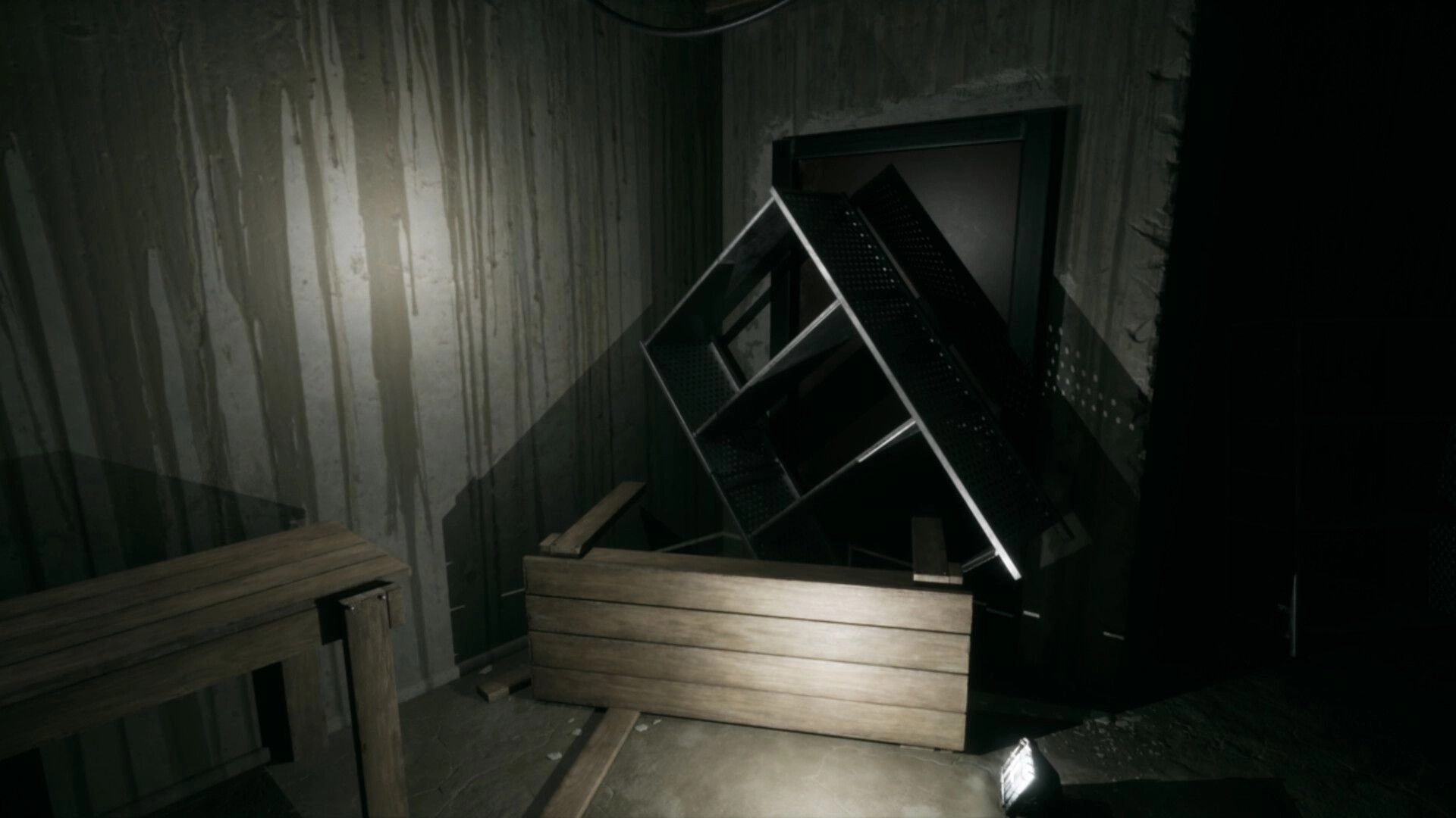 LAG KILLS: Flashlight-lit basement corner with toppled metal shelf and wooden boards blocking a door.