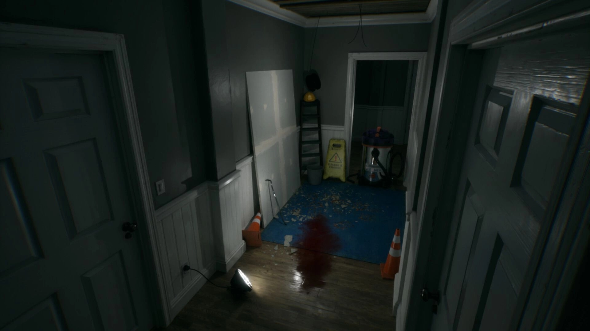 LAG KILLS: First-person view down a dim hallway with blood trail, cones, ladder, and wet floor sign.