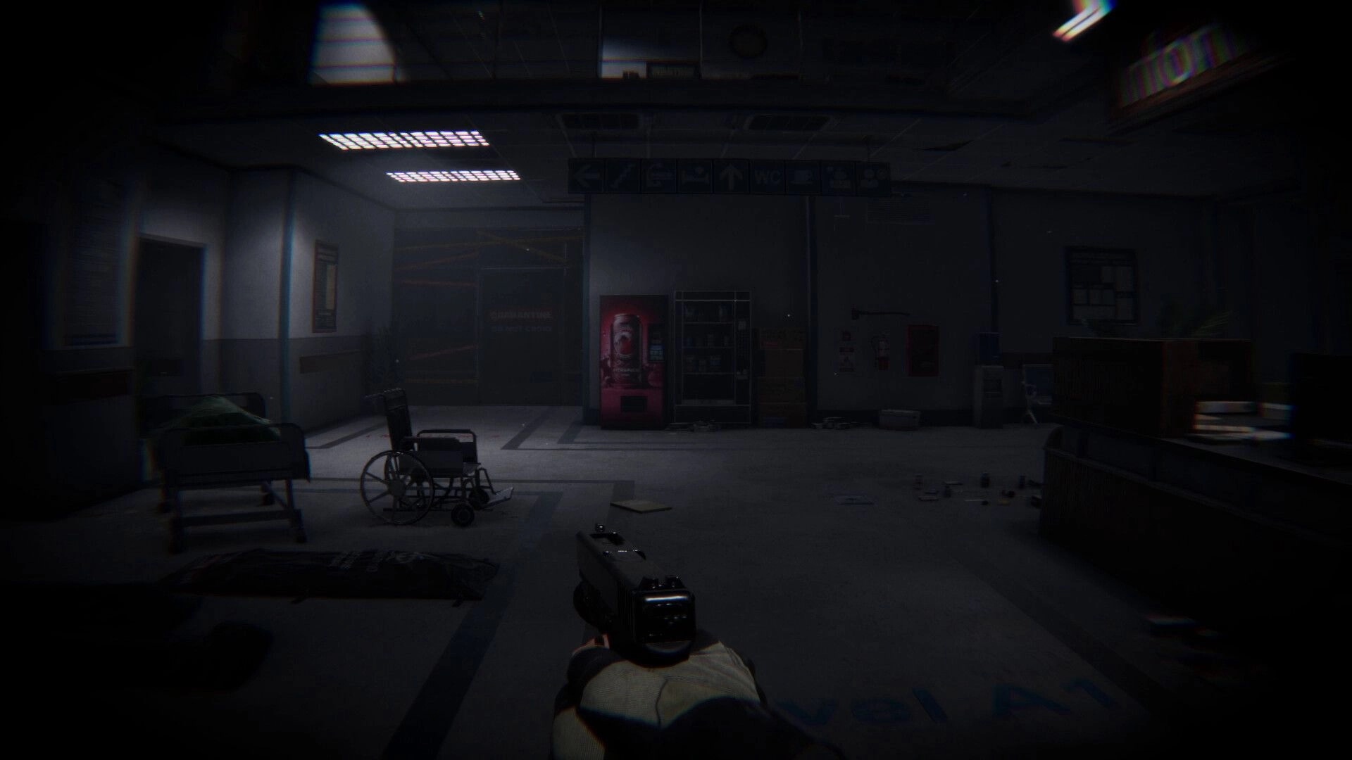 Lens Of Fear: First-person pistol aiming in abandoned hospital lobby with wheelchair and vending machines.