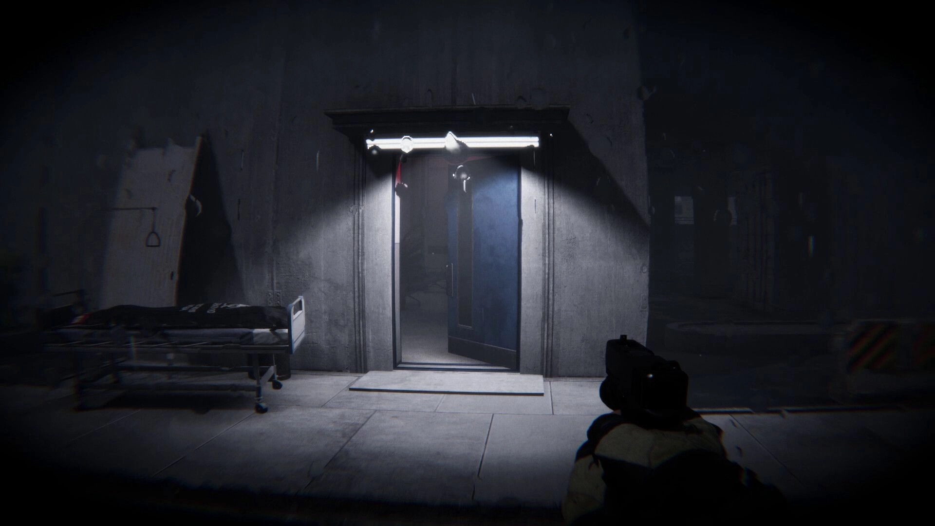 Lens Of Fear: First-person aim at a lit doorway beside a gurney in a dim concrete hallway.