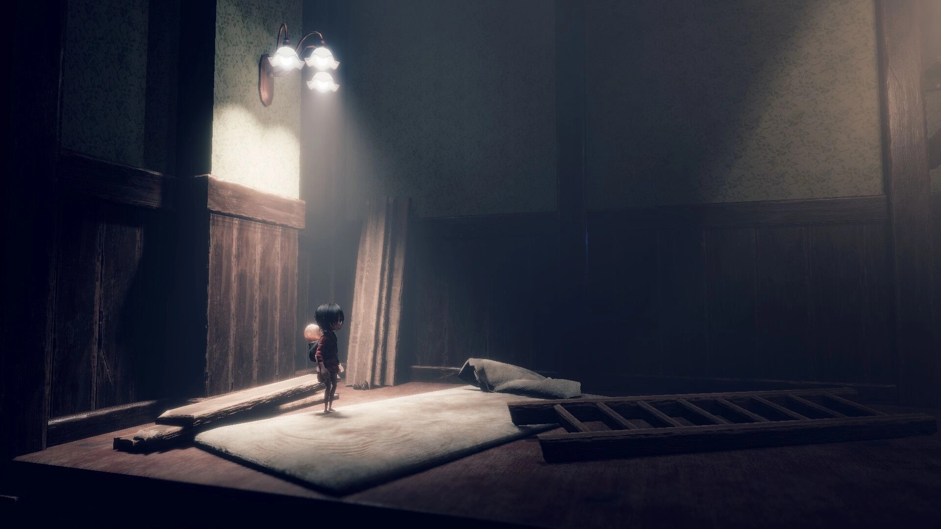 Lull: Girl with baby on her back stands in a dim room with boards, mattress, and ladder debris.